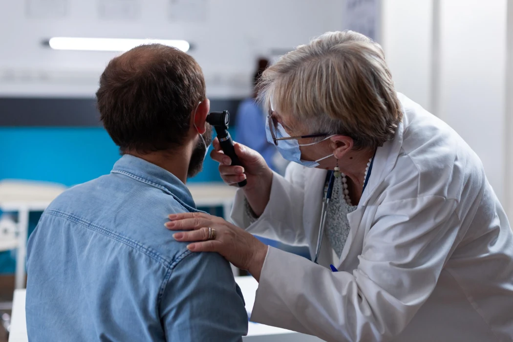 Female pharmacist performing ear wax microsuction on a patient